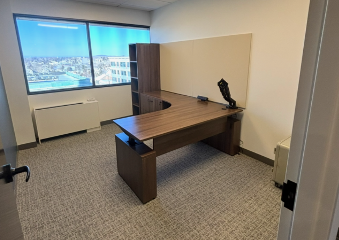an office with a dark brown ergonomic desk. 