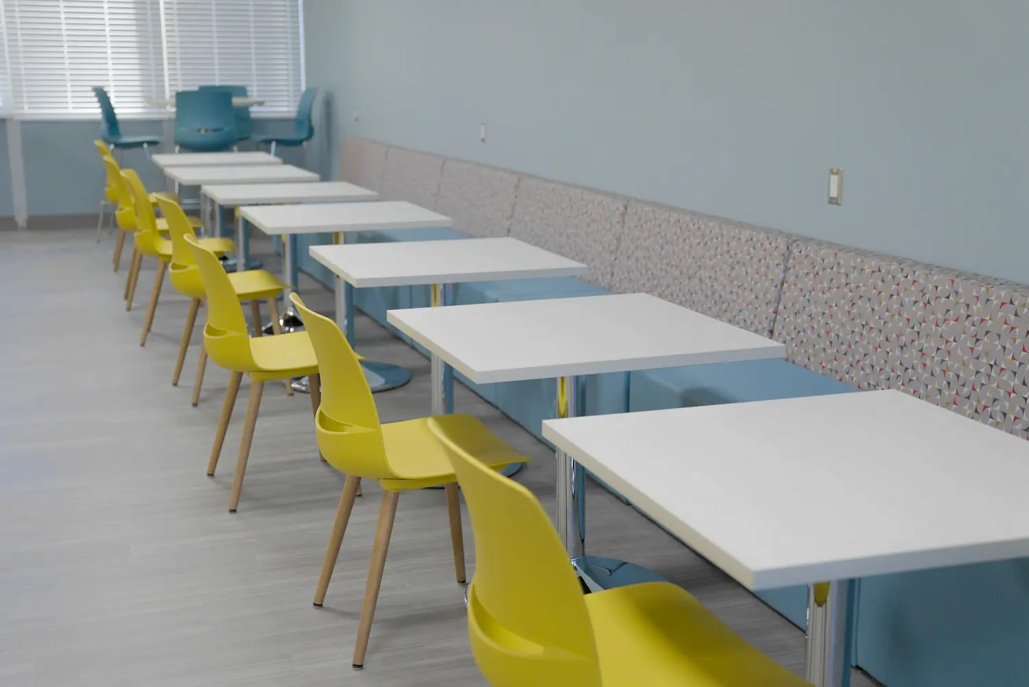 a row of yellow and blue chairs at white tables.